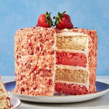 layered strawberry and vanilla cake covered in strawberry crunch and topped with fresh strawberries