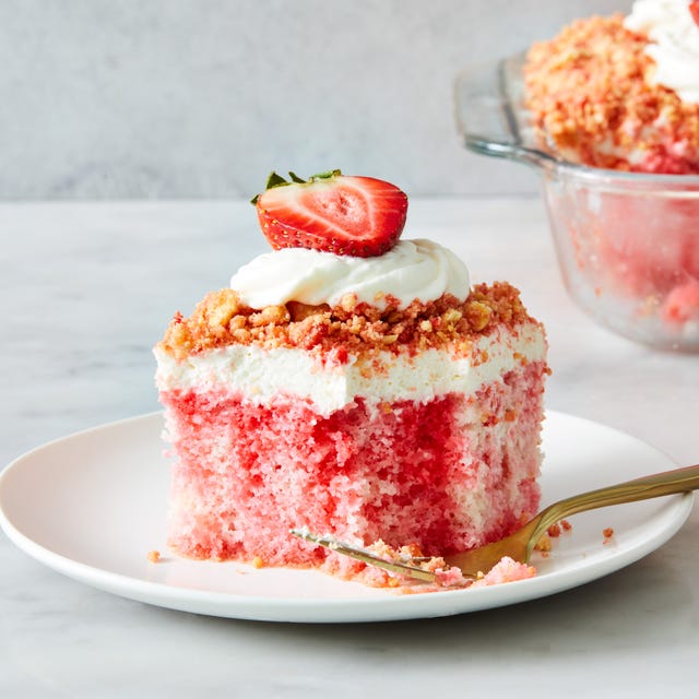 strawberry crunch poke cake with a crumble topping, whipped cream and strawberries