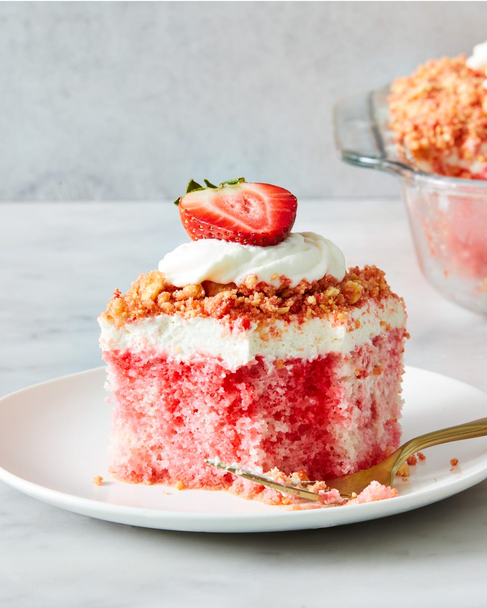 strawberry crunch poke cake with a crumble topping, whipped cream and strawberries