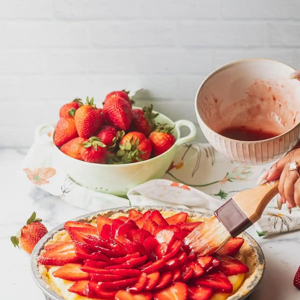 a plate of strawberries and a knife next to a bowl of strawberries