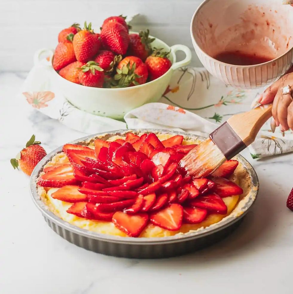 a plate of strawberries and a knife next to a bowl of strawberries