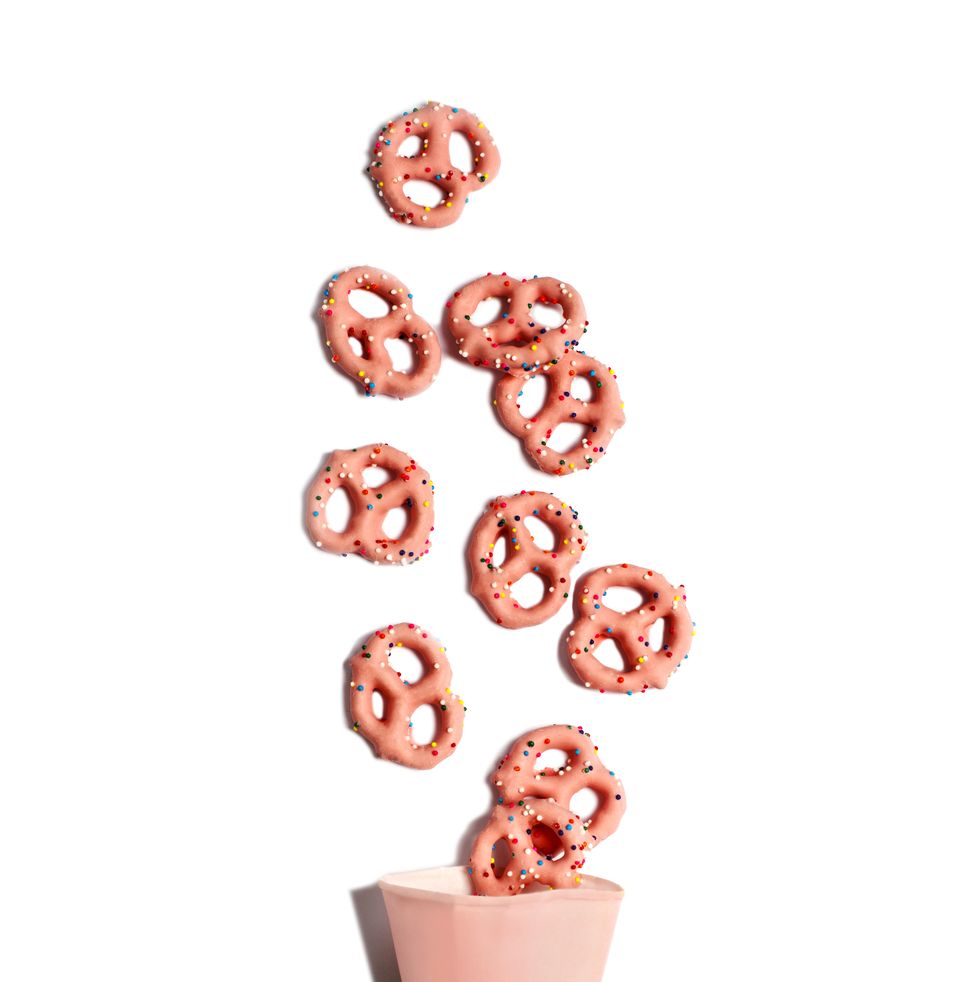 strawberry flavoured yogurt covered pretzels in paper cone on white background
