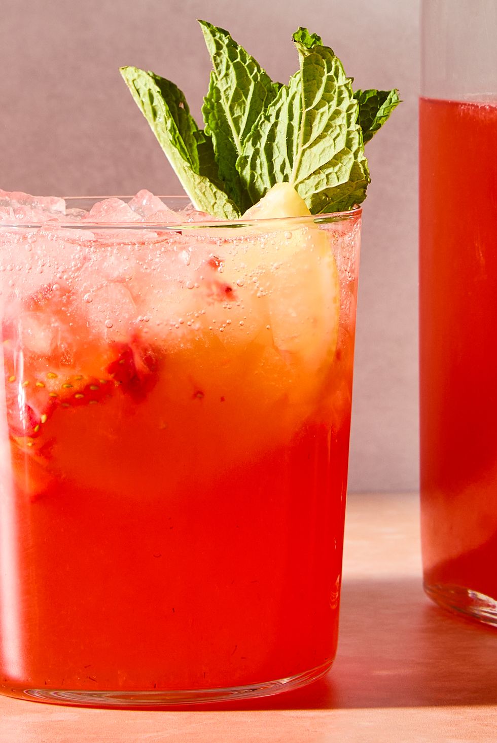 strawberry lemonade shrub with ice in a glass with mint