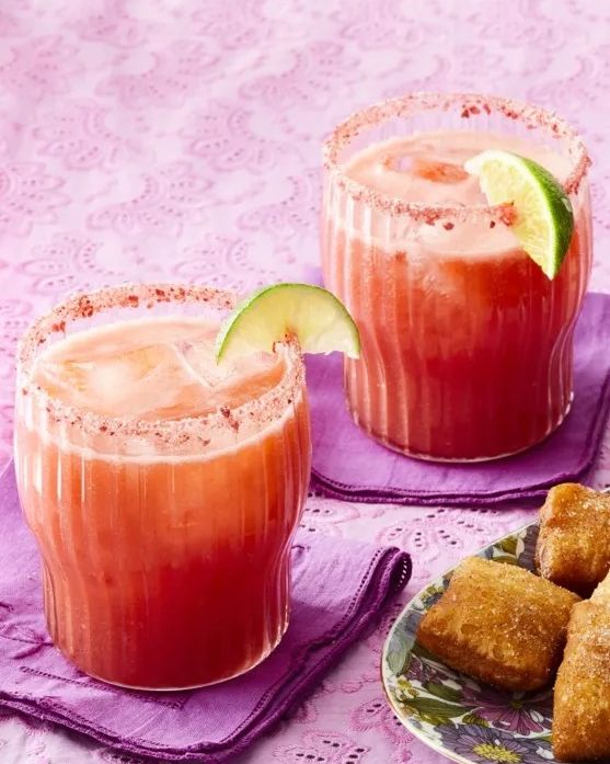 strawberry margaritas with lime wedges on purple linen napkins