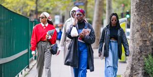 paris, france   october 01 a guest l wears a scarf  bandanna over the head, sunglasses, large golden earrings, a white shirt, a red oversized wool pullover, a dior saddle bag made of black leather, gray pants, a chain belt, sneakers, holds a fashion magazine stylist  a guest m wears a blue and burgundy bandanna over the head, a black long oversized leather jacket, a blue denim jumpsuit, black shoes  a guest r wears a black leather jacket, blue flared jeans, during paris fashion week   womenswear spring summer 2021, on october 01, 2020 in paris, france photo by edward berthelotgetty images