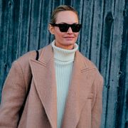 a woman at fashion week wears a turtleneck sweater to illustrate a guide to the best winter sweaters for women 2022