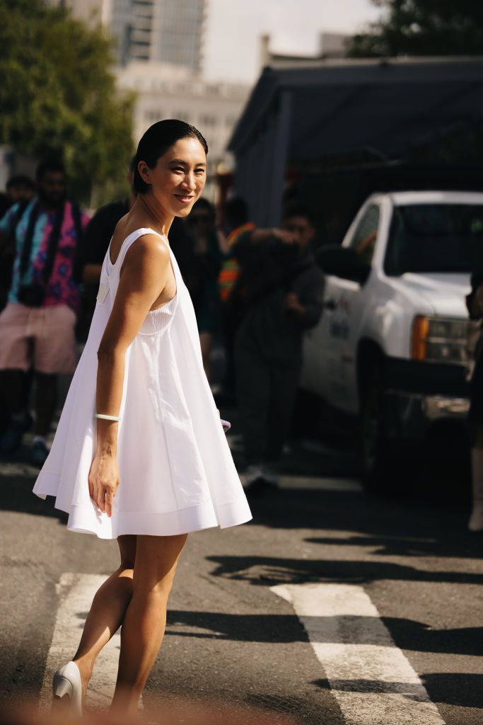 a woman Eva Chen wearing a white mini dress while crossing the street in a list of the best travel outfits for women in 2024