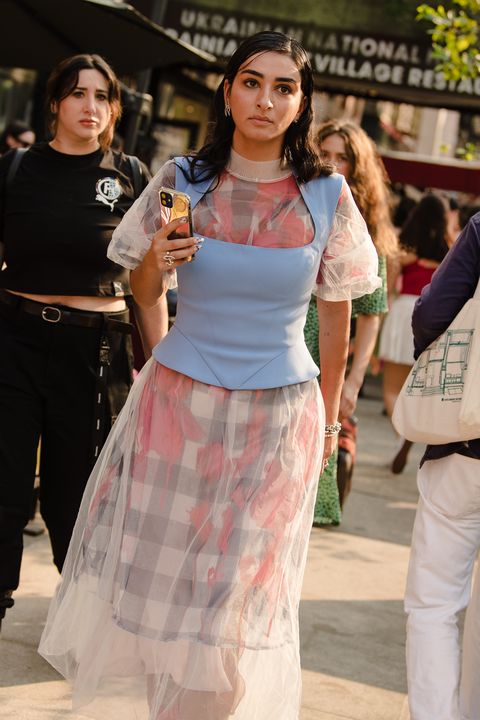 a new york fashion week attendee wearing a corset over a dress that mixes plaids, florals, and an overlay