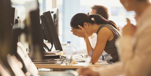 Stressed businesswoman with head in hands at office desk