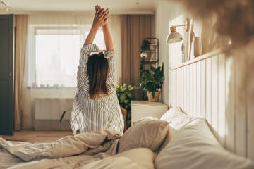 woman stretching in bed after wake up, back view