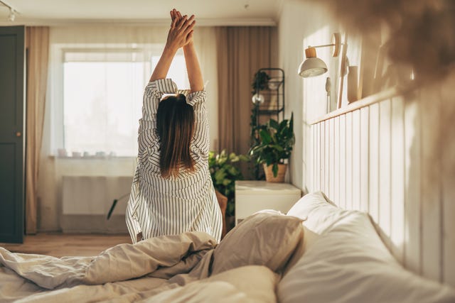 woman stretching in bed after wake up, back view