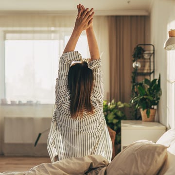 Woman stretching in bed after wake up, back view woman stretching in bed after wake up, back view