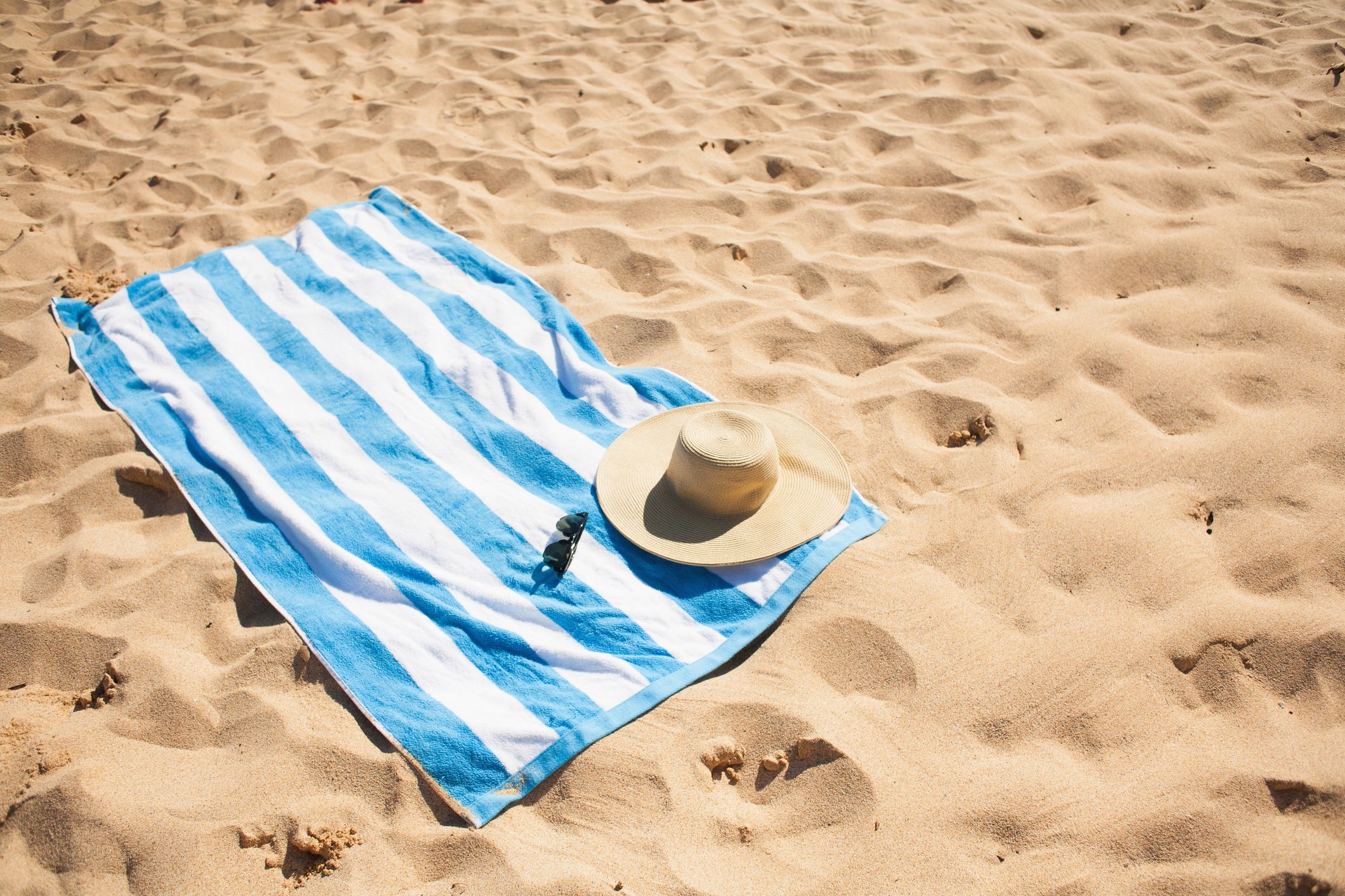 https://hips.hearstapps.com/hmg-prod/images/striped-beach-towel-on-sand-with-hat-and-glasses-royalty-free-image-1595590181.jpg