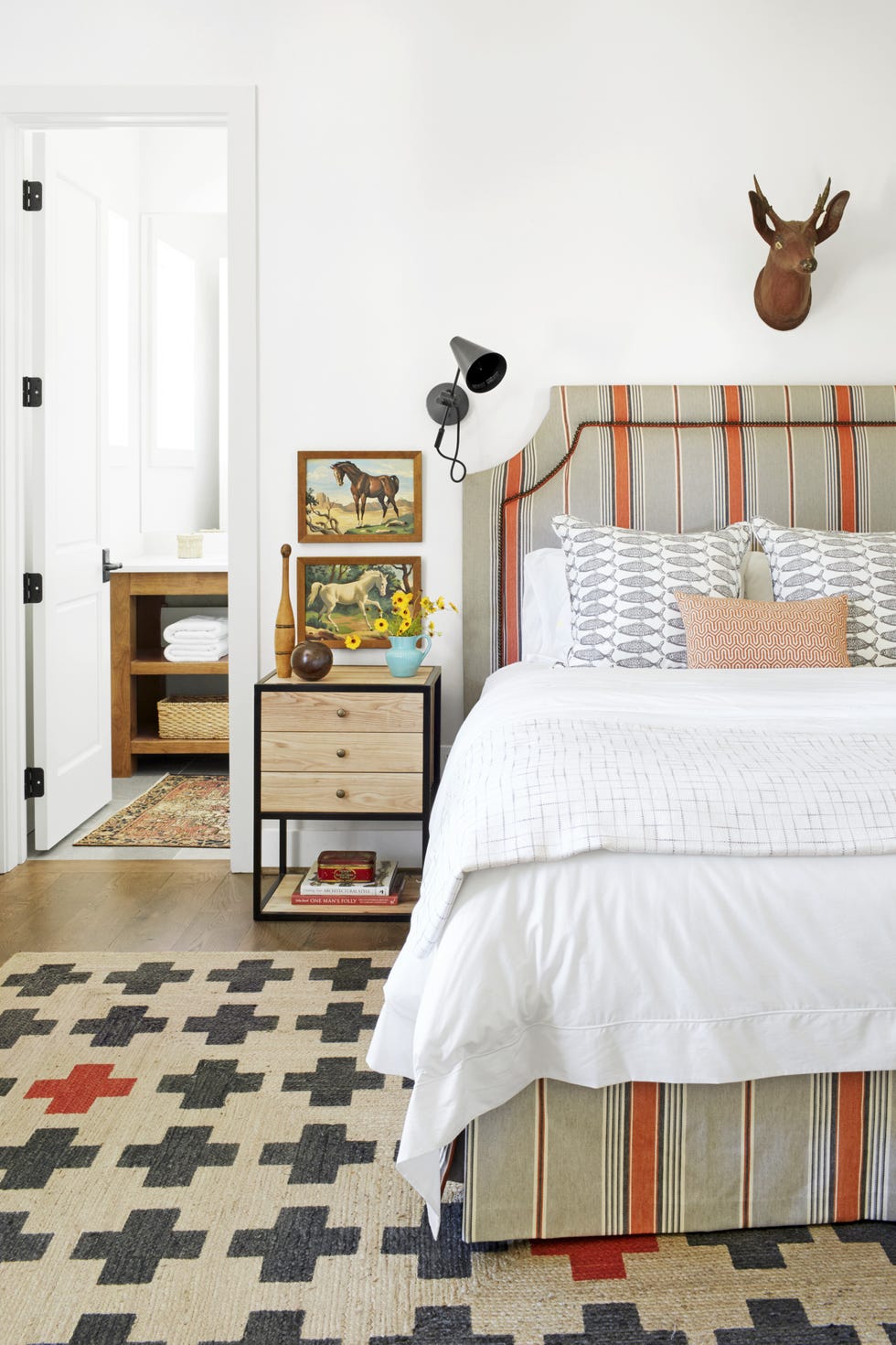 striped upholstered headboard and a graphic rug with crosses