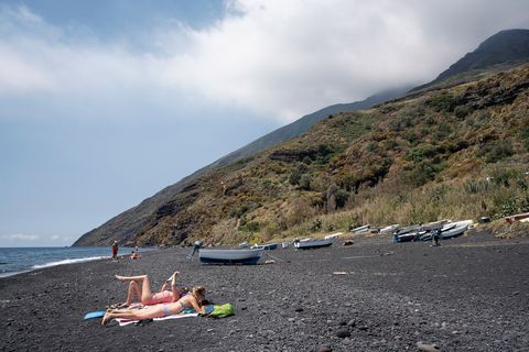 Twee vriendinnen zonnebaden op een van de zwarte zandstrandjes van Stromboli