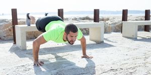 strong man doing feet elevated push ups at seaside