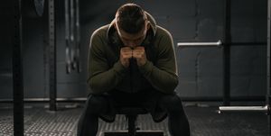 strong sporty man sitting on gym bench suffering breakdown to overcome