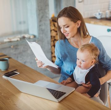 best stay at home mom jobs woman holding baby while looking at paperwork and laptop