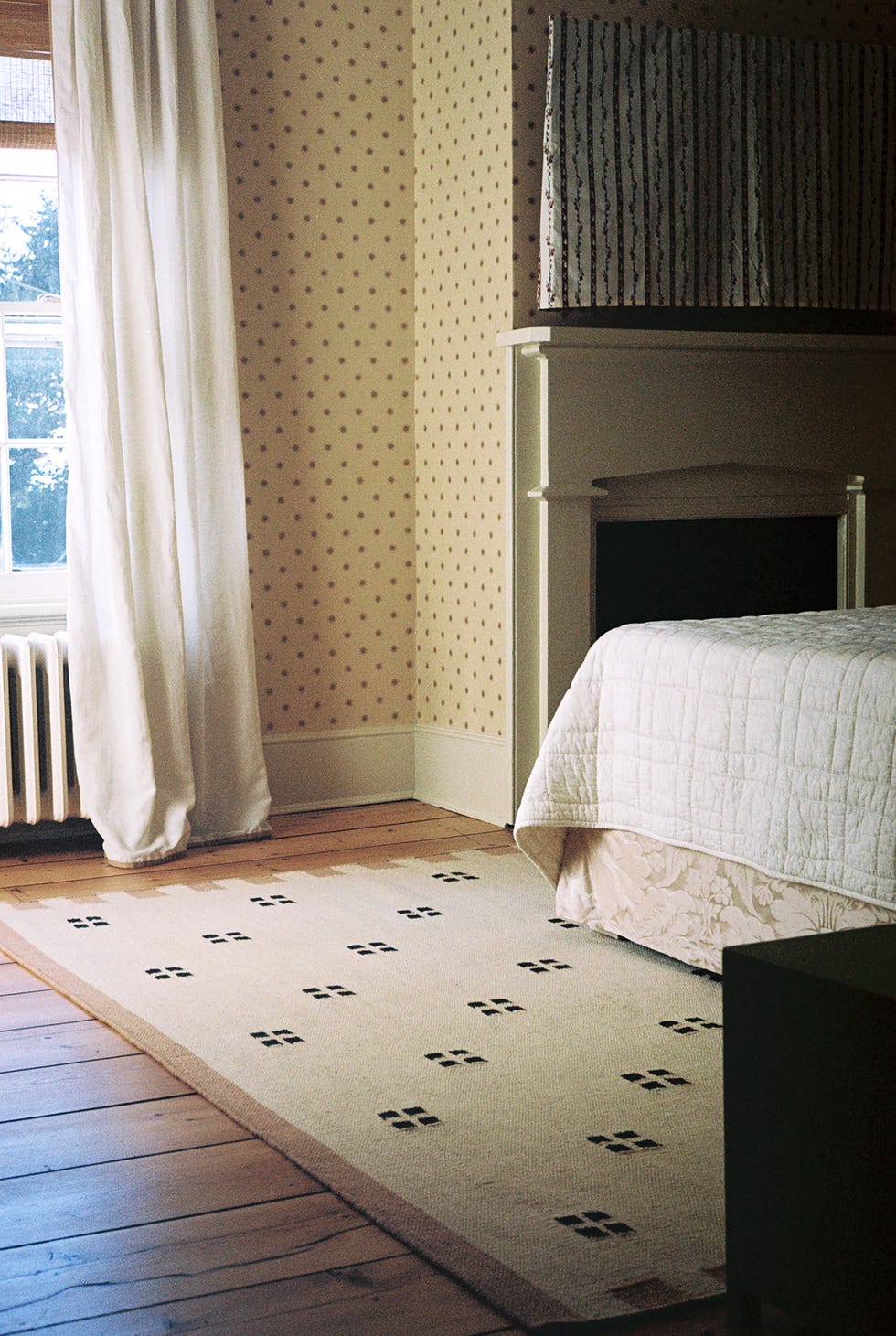 patterned rug on top of wood plank floors in a bedroom with patterened wallcovering