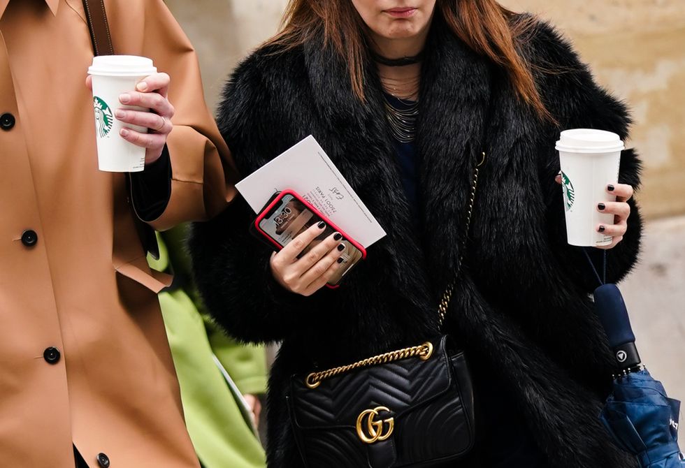 paris, france march 02 a guest l wears a light brown leather coat, blue jeans a guest r wears necklaces, a black fur coat, a black gucci bag, a navy blue dress, holds a cup from starbucks coffee, outside giambattista valli, during paris fashion week womenswear fallwinter 20202021, on march 02, 2020 in paris, france photo by edward berthelotgetty images