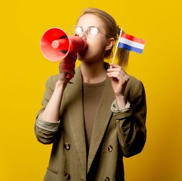 blonde vrouw met megafoon en nederlandse vlag