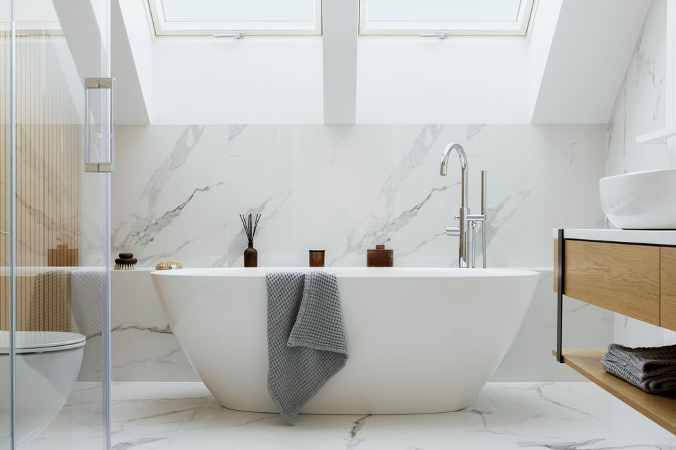 stylish bathroom interior design with marble panels. bathtub, towels and other personal bathroom accessories. modern glamour interior concept. roof window. template."n