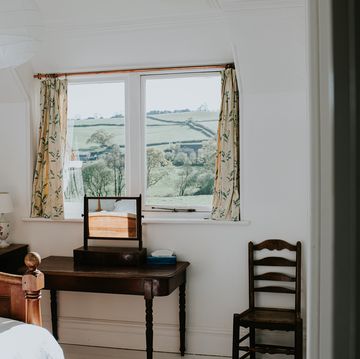 a stylish, tidy bedroom painted white, with a beautiful countryside view