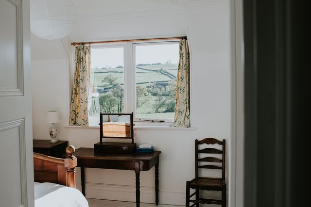 a stylish, tidy bedroom painted white, with a beautiful countryside view