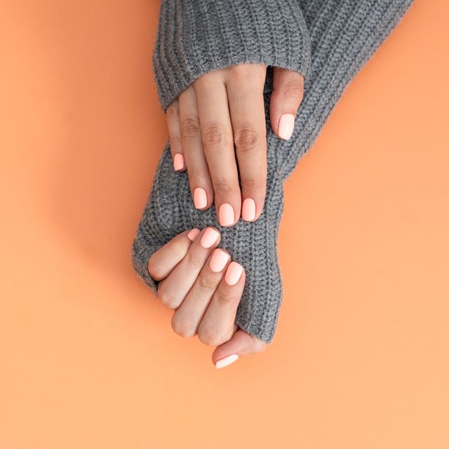 Stylish trendy female manicure. Beautiful young woman's hands on Living Coral background. Color of the year 2019 concept.