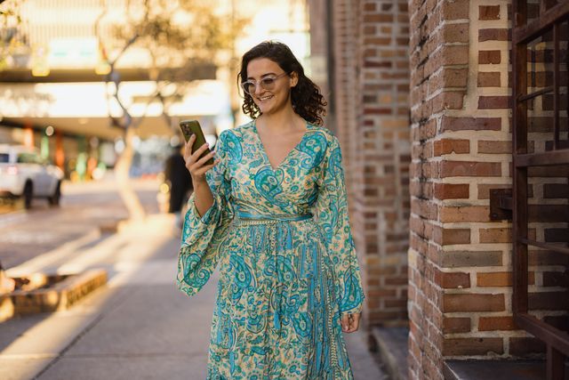 stylish woman walking down the street using smartphone