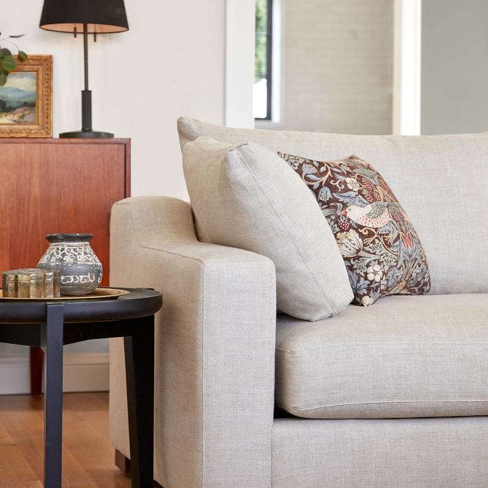 a grey couch with a white pillow a grey couch with a white pillow