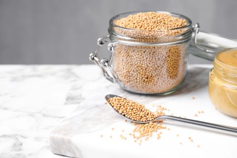 mustard seeds on white marble table spoon