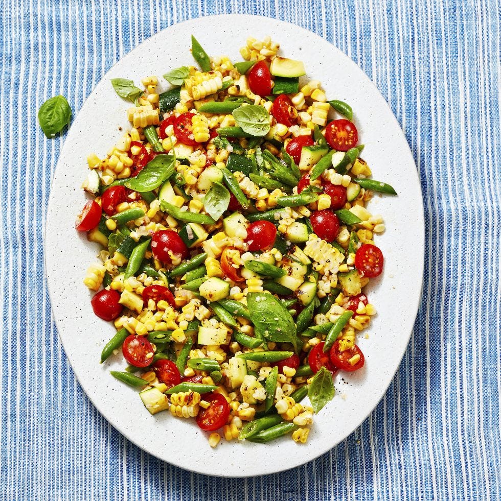 corn, red small tomatoes, zucchini and green beans on a white plate