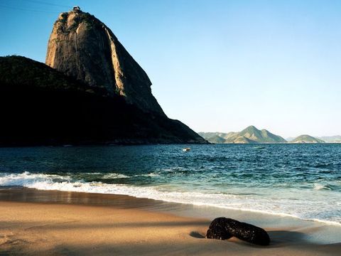 De Sugarloafberg steekt hoog uit boven een strand in Rio de Janeiro een stad die bekend staat om de geweldige strandcultuur