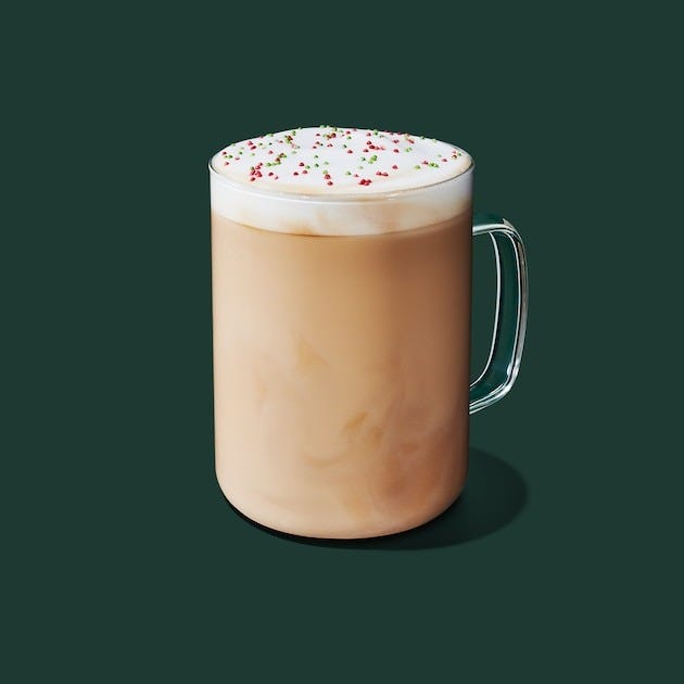 coffee beverage topped with whipped cream and festive sprinkles in a clear glass mug