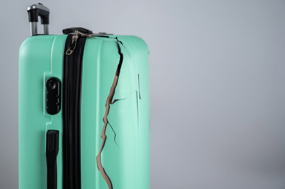 close up of a broken plastic suitcase on a white background