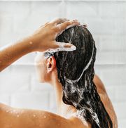 young woman in bathroom taking a shower and washing her hair