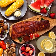summer bbq or picnic food top down view table scene over a dark wood background