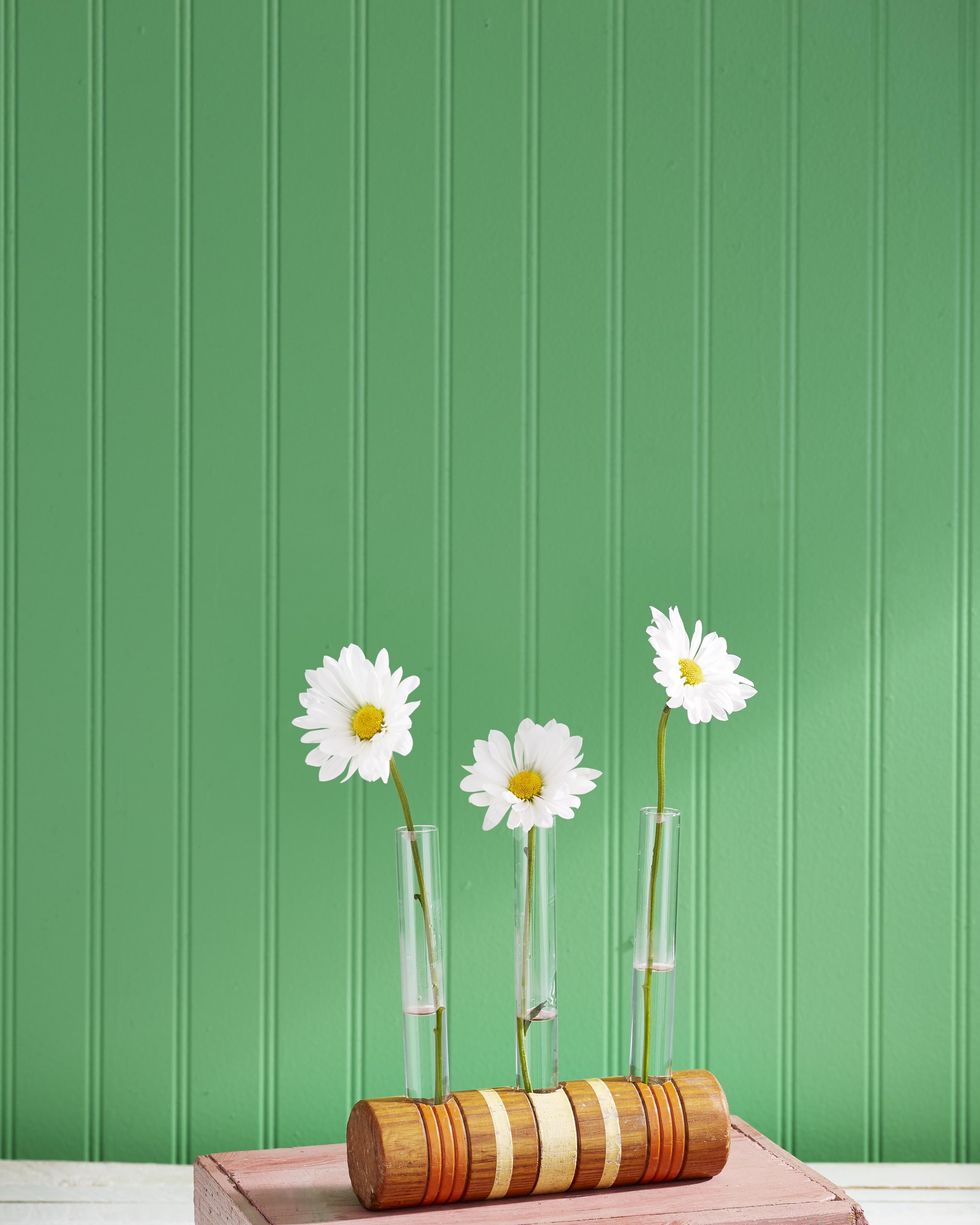 a trio of daisy filled bud vases nestled in holes drilled in the head of a croquet mallet for a summer craft project