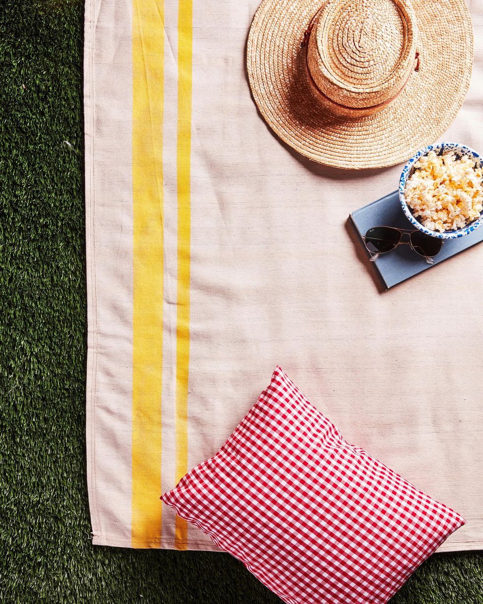 picnic blanket made of a drop cloth painted with two yellow stripes, one thick and one thin, along one side for a summer craft project