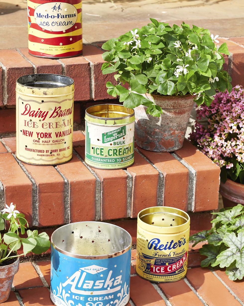 vintage ice cream tin with holes drilled into them and turned into luminaries set on outside brick steps