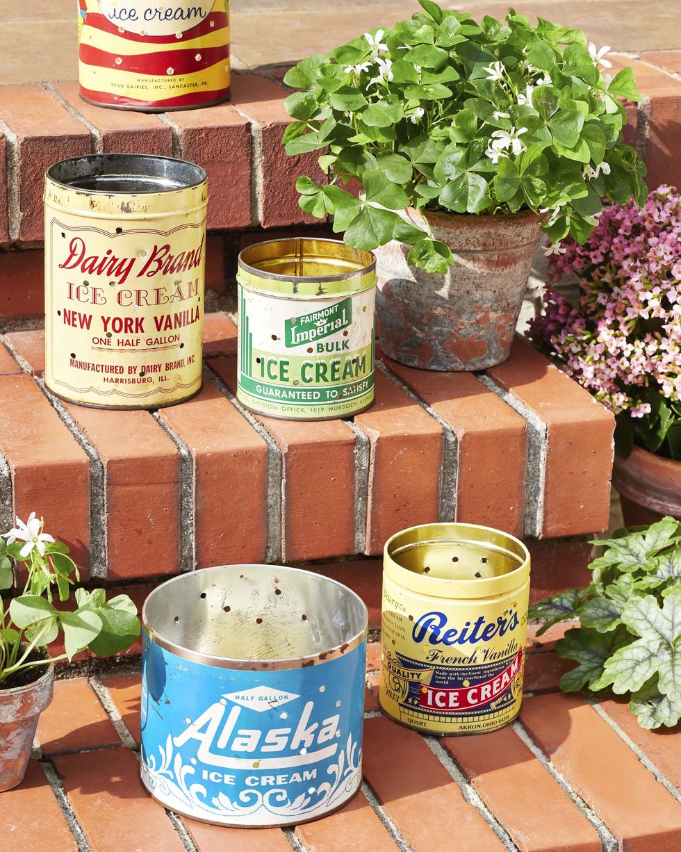 vintage ice cream tin with holes drilled into them and turned into luminaries set on outside brick steps