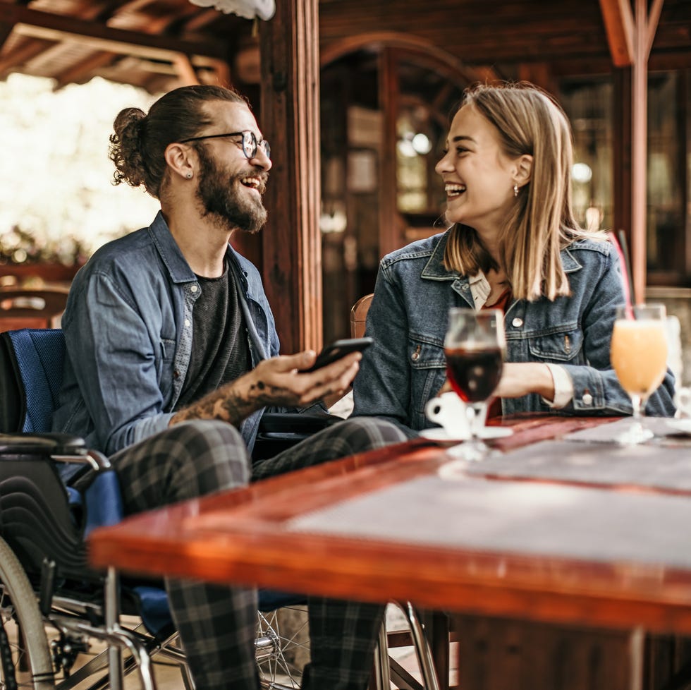 man in wheelchair and blonde woman eating at an outdoor restaurant on a summer date