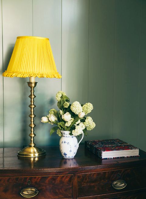 green wall and antique dresser with yellow lamp