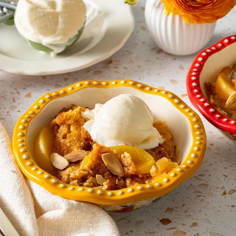 peach dump cake in bowl with vanilla ice cream and almonds