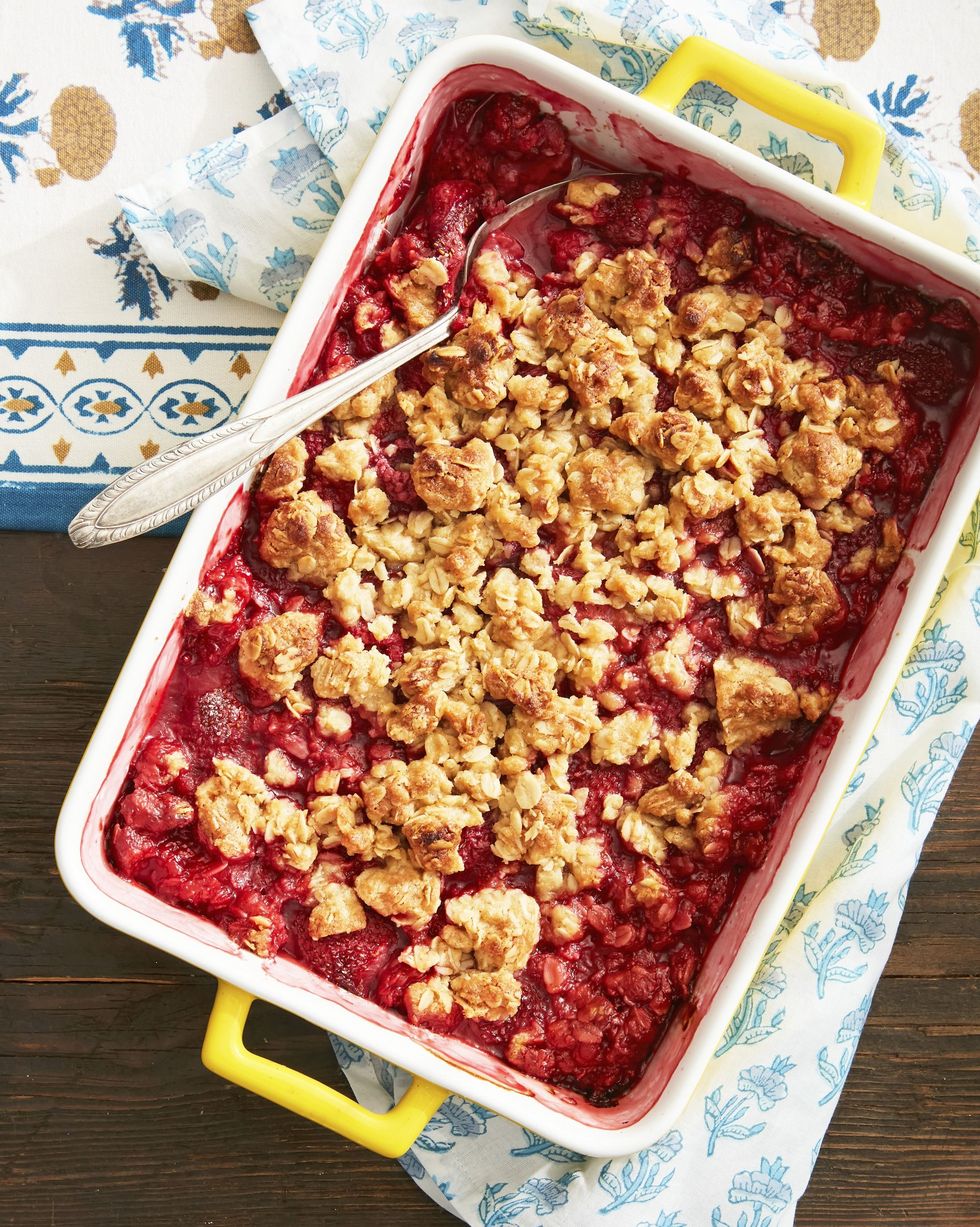 strawberry fruit crisp in a rectangle baking dish with a spoon for serving