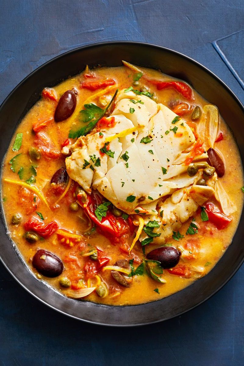 tomato poached cod with capers and olives in a bowl