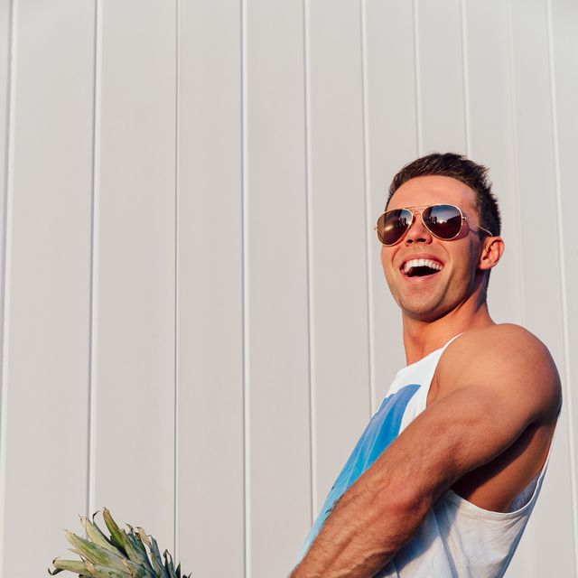 Summer photo of joyful man with pineapple.