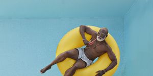 summer quotes bald senior man drinking juice while relaxing in yellow inflatable ring