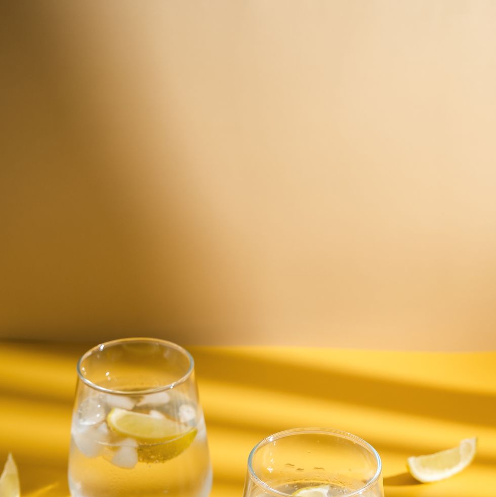 refreshing sparkling drink with ice cube on a yellow background
